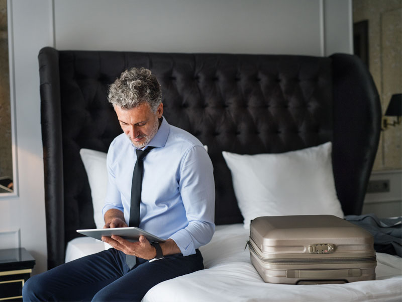 mann sitz auf hotelbed und arbeitet